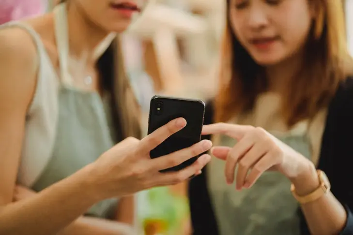 Zwei junge Frauen schauen auf ein Smartphone.
